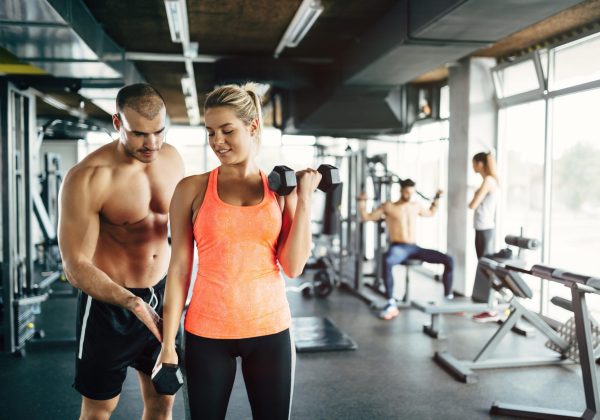 Personal trainer giving instructions to student  in gym